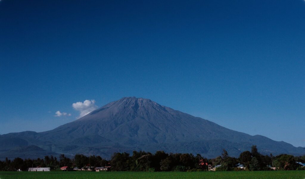 Mount Meru volcanic landscape under clear blue sky near Arusha — airport transfer route