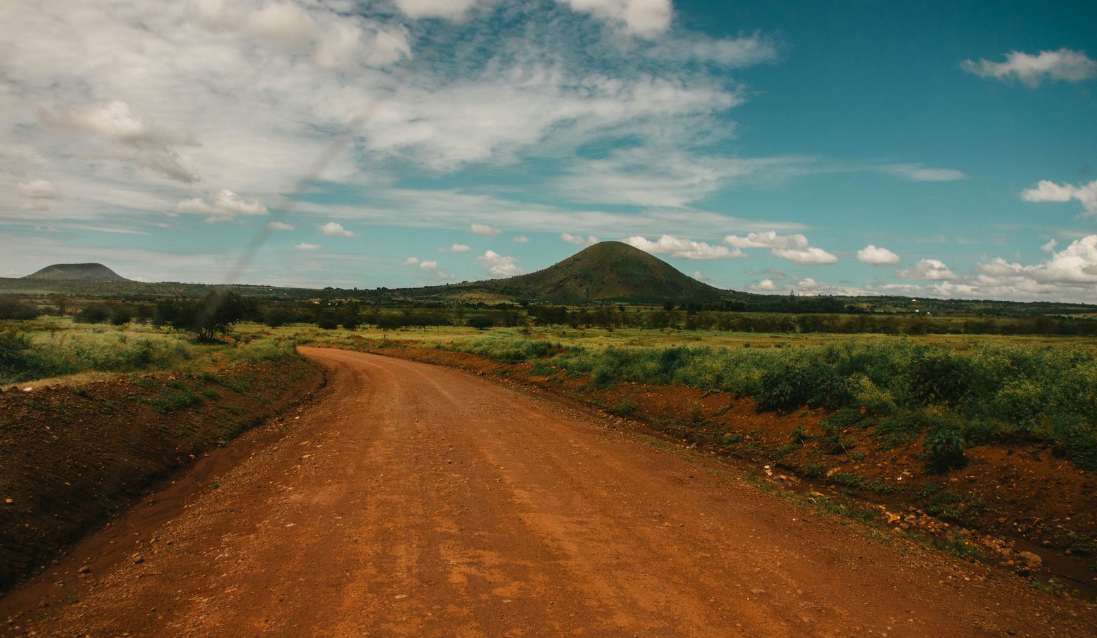 Rwanda Kigali Transfers & 4x4 5 Open red-dirt road through green hills for Rwanda self-drive